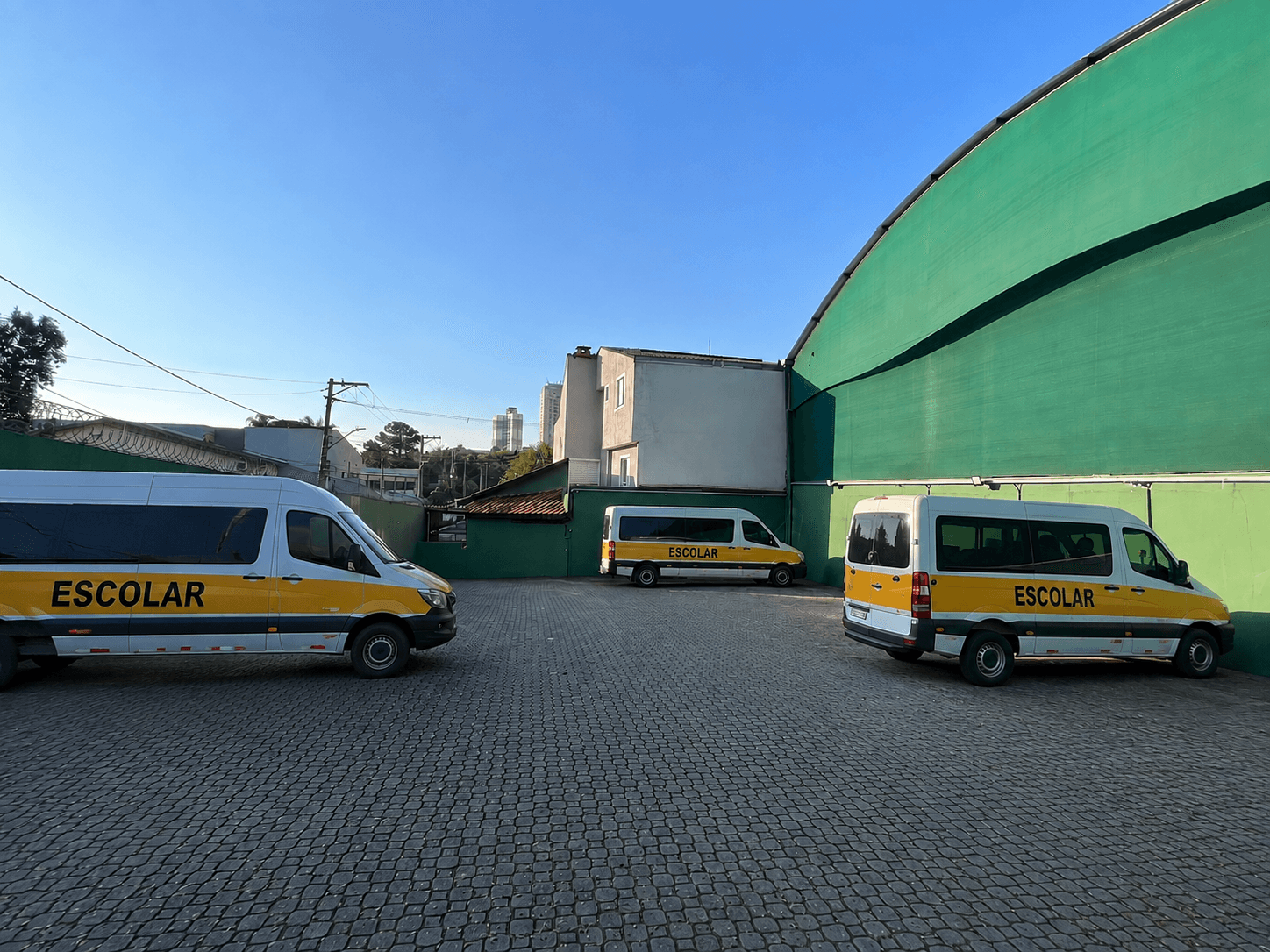 Estacionamento interno com vans escolares para embarque e desembarque seguro dos alunos