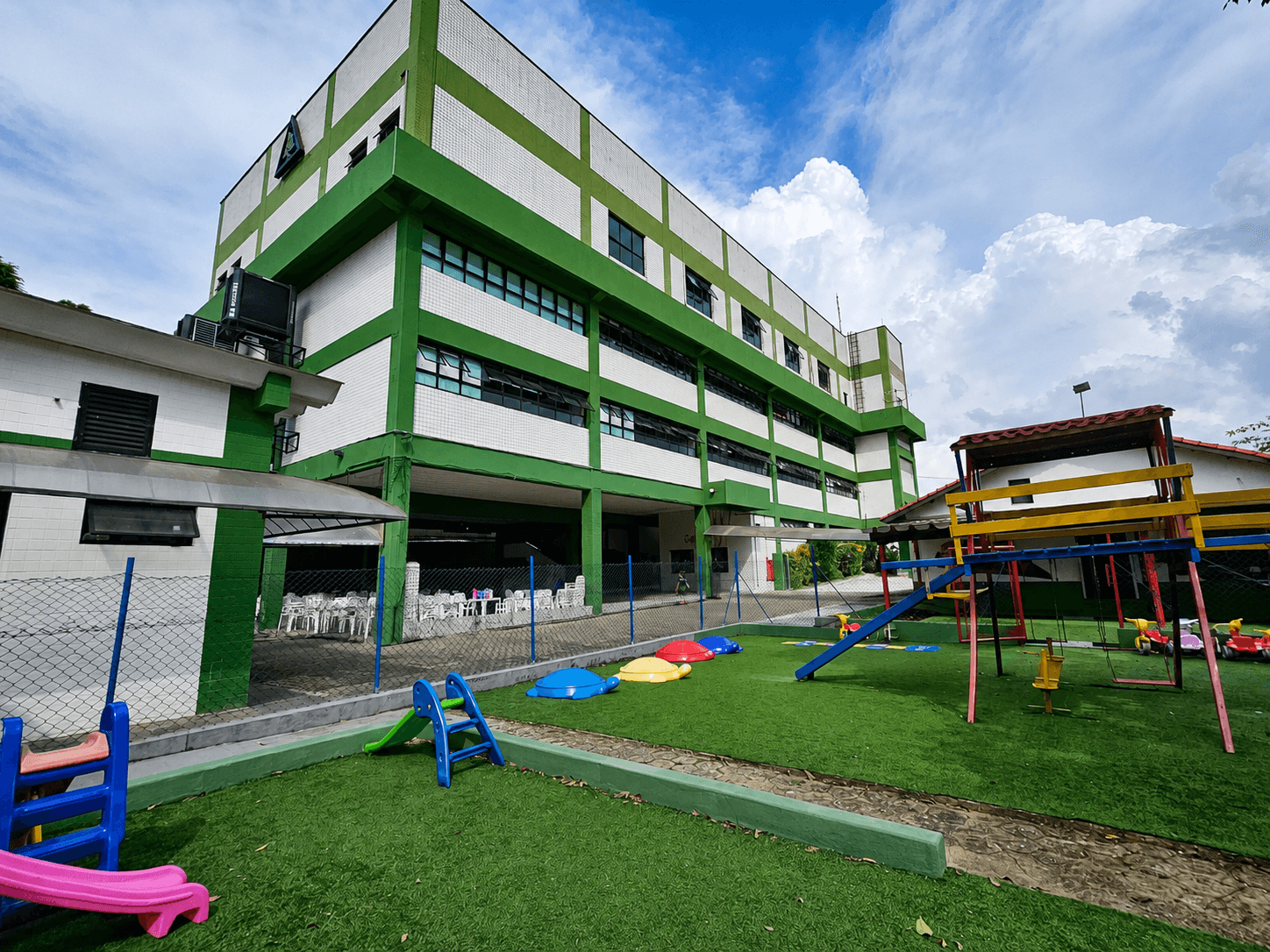 Prédio principal do Colégio Penha de França com playground infantil e área externa